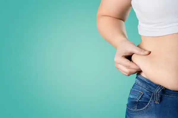Image of woman pinching her love handles to show weight gain Swindon