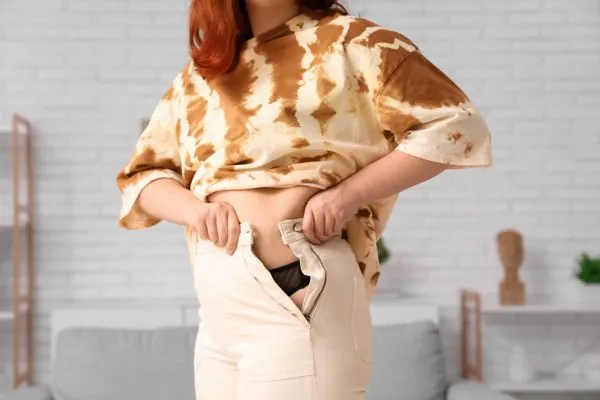 Image of woman trying to do her trousers up after pregnancy weight gain Swindon